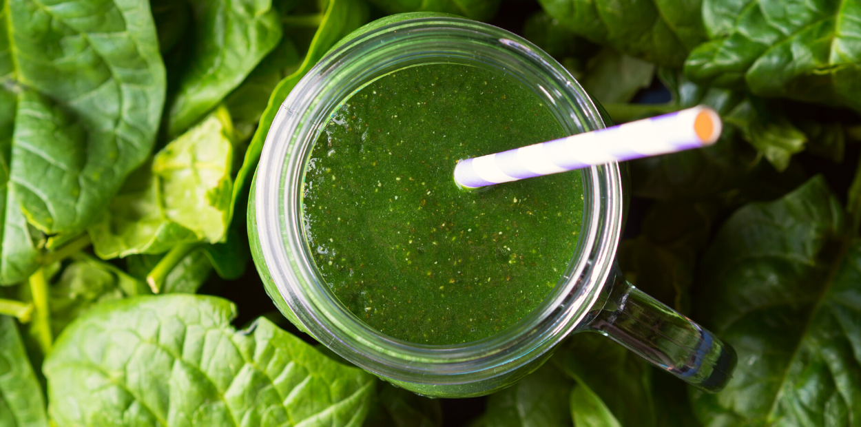 Top-view of a green smoothie surrounded by spinach